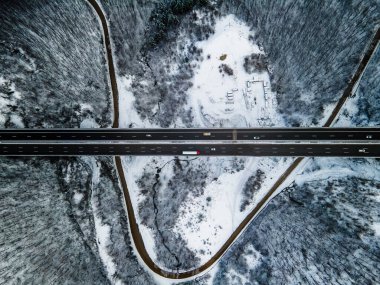 Harika bir yol manzarası. Nehir ve ağaçlarla muhteşem bir kar manzarası. Arabalar yolda gidiyor. Kar aracı görüntüsü.
