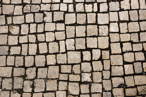 Mosaic of small marble cubes. sidewalks and squares formed by stone carpet with squares. Old cobblestones. High quality photo