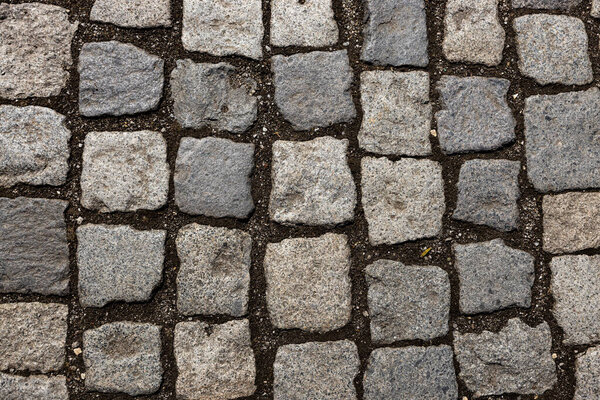Mosaic of small marble cubes. sidewalks and squares formed by stone carpet with squares. Old cobblestones