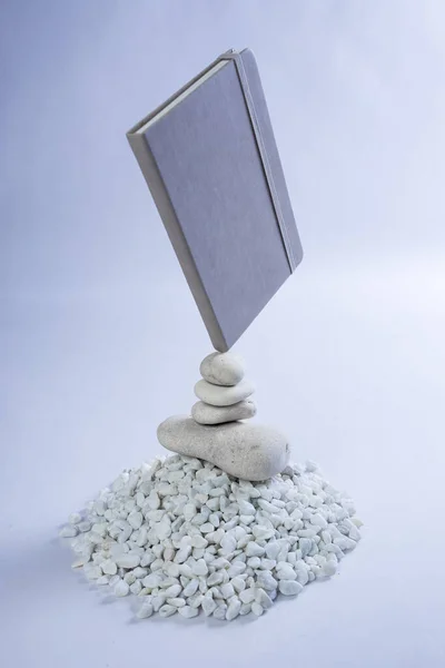 Grey notebook on a mountain stack of white rocks with a reflection. Studio photo of a product notebook. High quality photo
