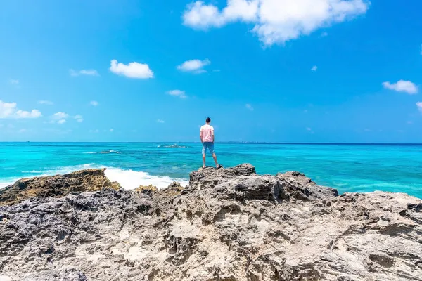 Задний вид человека, стоящего на скалах и смотрящего на море и небо — стоковое фото