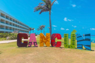 Cancun, Meksika. 30 Mayıs 2021. Park 'ta, ağaç ve denize karşı otel binaları arasında renkli Cancun işareti