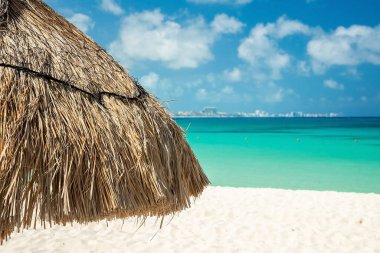 Yaz boyunca bulutlu gökyüzüne karşı güzel deniz suyu yüzeyi olan kumsaldaki saman örtüsünü kapat.