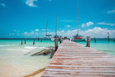 Cancun, Meksika. 30 Mayıs 2021. Kumdan denize giden ahşap iskele demirli yatlarla ya da su yüzeyinde yelkenli tekneleriyle