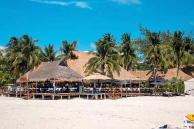 Cancun, Meksika. 30 Mayıs 2021. Yaz tatili boyunca kumlu sahildeki restoranda saman örtüsü altında dinlenen turistler