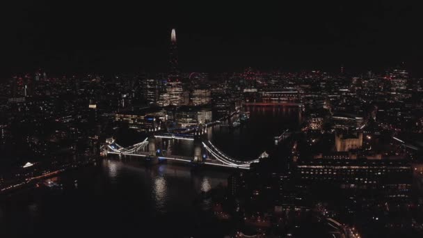 Widok z powietrza na oświetlony Tower Bridge i panoramę Londynu w nocy, Wielka Brytania. — Wideo stockowe
