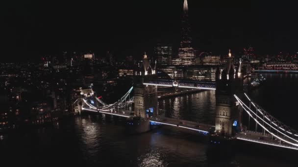 Widok z powietrza na oświetlony Tower Bridge i panoramę Londynu w nocy, Wielka Brytania. — Wideo stockowe