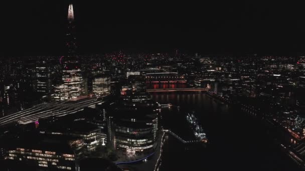 Vue aérienne vers le Tower Bridge illuminé et les toits de Londres la nuit, Royaume-Uni. — Video