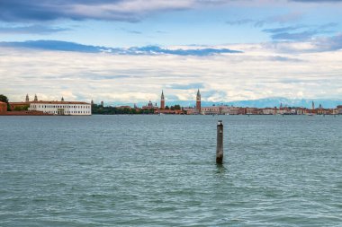Arkaplanda ahşap direkli güzel deniz suyu yüzeyi manzarası ve şehir binaları.