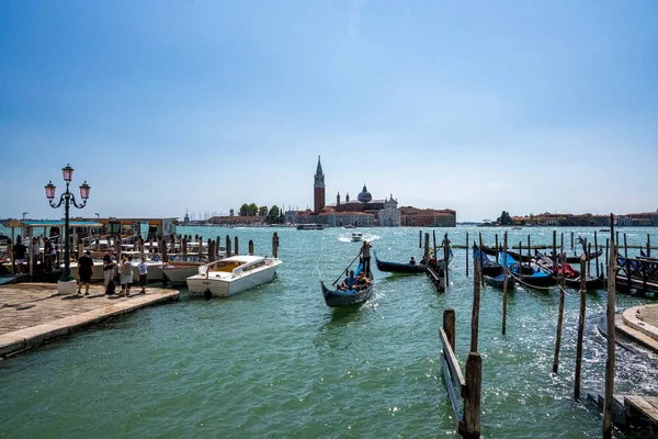 Toeristen reizen in boten over zeewater oppervlak samen met afgemeerde gondels en stadsgezicht op de achtergrond — Stockfoto