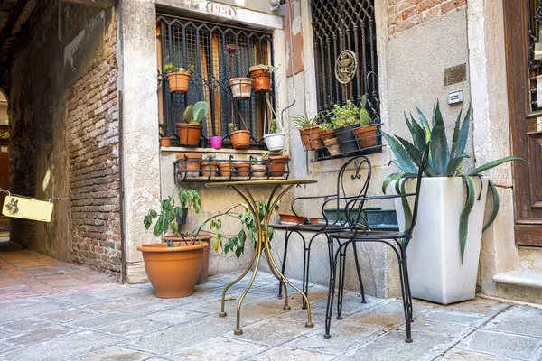 Традиционный дом с горшечными растениями на кирпичной стене со стульями и столами на открытом воздухе — стоковое фото