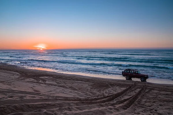 Carro Vermelho Offroad Estacionado Praia Areia Durante Pôr Sol Frente — Fotografia de Stock