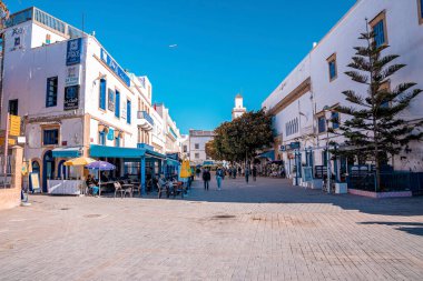İnsanlar alışveriş yapıyor ve işlek caddelerde market tezgahları ve dükkanlarıyla yürüyor.