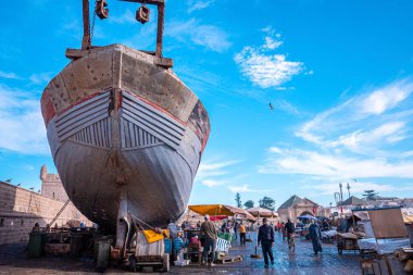 Marinadaki balık pazarının yanındaki tekne bulutlu gökyüzüne karşı park edilmiş.
