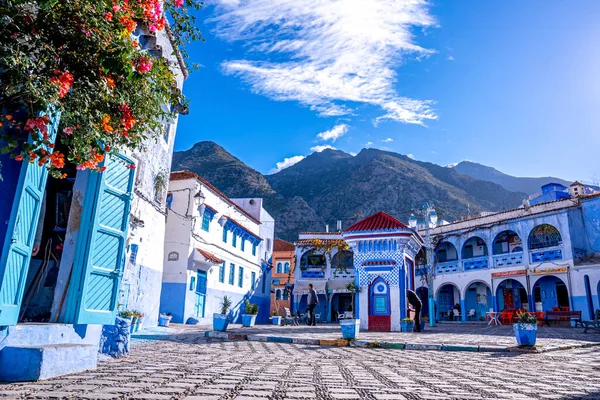 Drinking water outlet amidst cafe and residential structure, mountain in background — стоковое фото