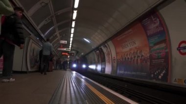 Londra metro istasyonu. Platformda hareket eden ağır çekim treni.