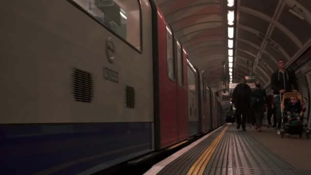 London Underground train station. Slow motion train moving by the platform. — Stockvideo