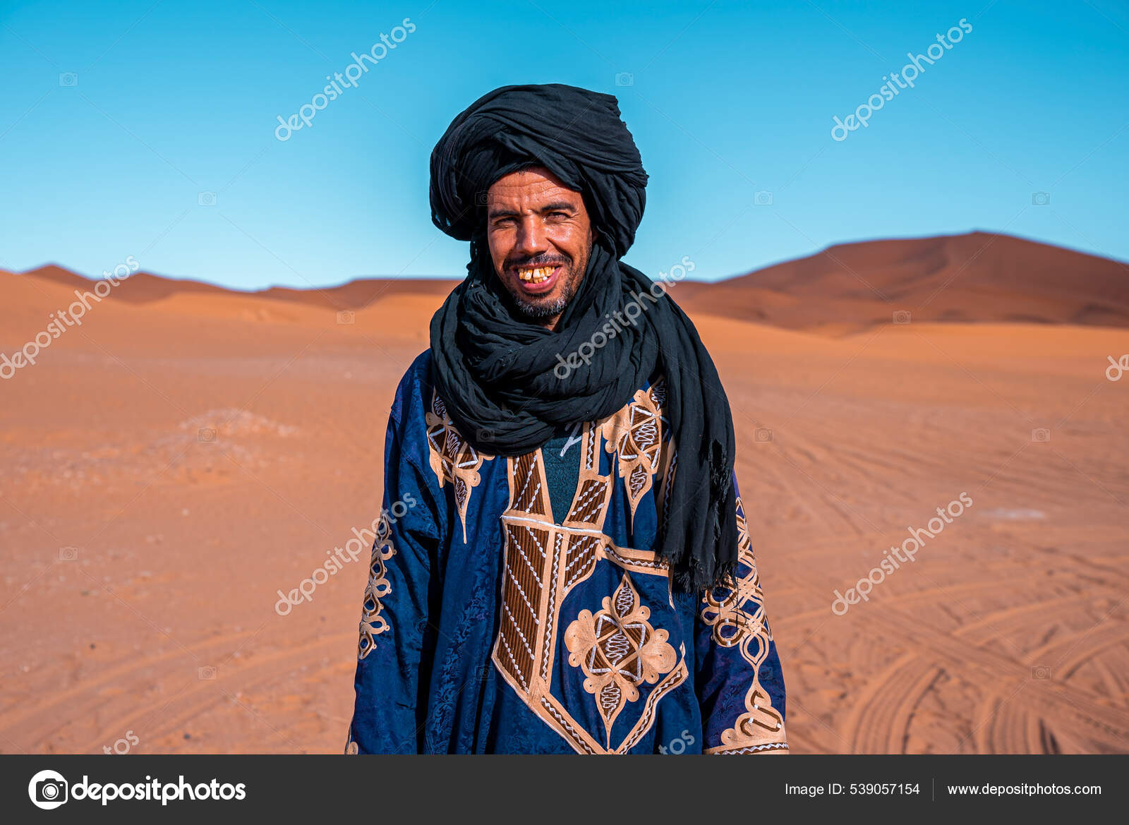 Bedouin man wears traditional clothes while standing in desert