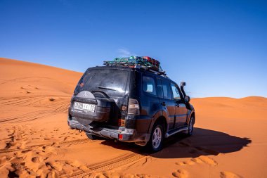 Black offroad vehicle parked in sand dunes on sunny summer day