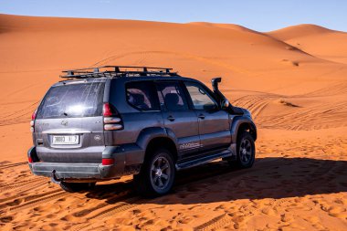 Black land cruiser prado parked in sand dunes on sunny summer day