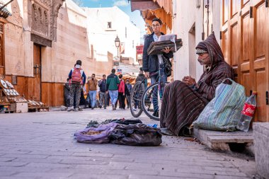 Crowded street scene with cyclist and homeless man in the foreground