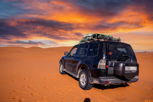 Black offroad vehicle parked in sand dunes against cloudy sky — Φωτογραφία Αρχείου