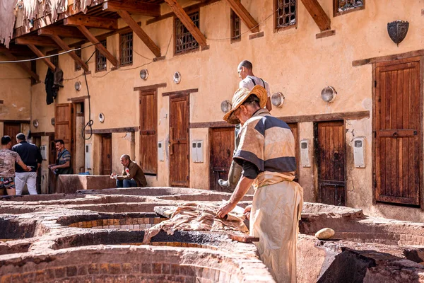 Man working in tannery using knife amidst brims of old stone water baths — Φωτογραφία Αρχείου
