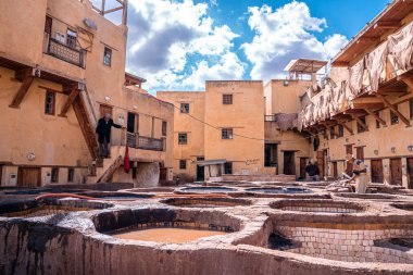 Dyed water fill in tanks in tannery against old residential building