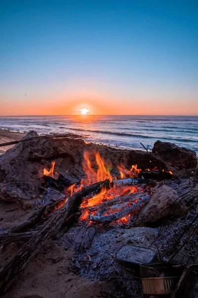 Bonfire met brandend brandhout tijdens prachtige zonsondergang op het strand — Stockfoto