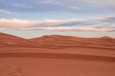 Amazing view of sand dunes with waves pattern in desert against cloudy sky