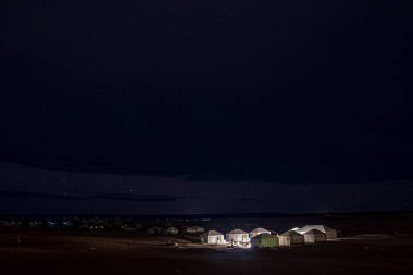 Glowing tourist tents on sand in desert landscape during night