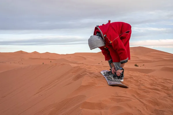 Hombre en ropa tradicional atadura de lija correa en dunas de arena contra el cielo — Foto de Stock