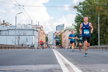 Tet Riga Maratonu sırasında Riga caddelerini geçen koşucular.