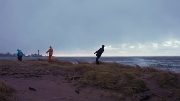 Gente luchando contra la tormenta y los fuertes hallazgos junto a la orilla del mar — Vídeo de stock