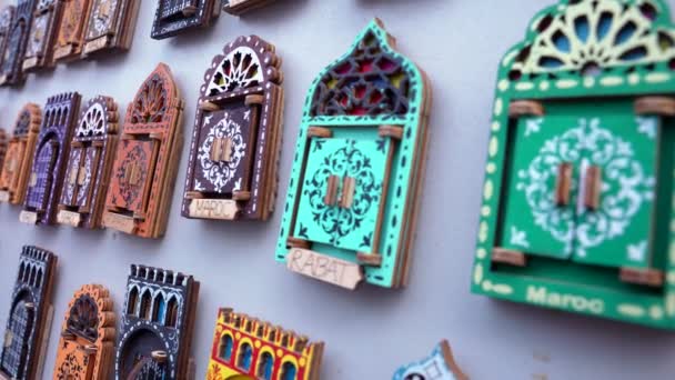 Різноманітність малих дерев'яних дверей у формі дизайну магнітів для продажу на місцевому базарі — стокове відео