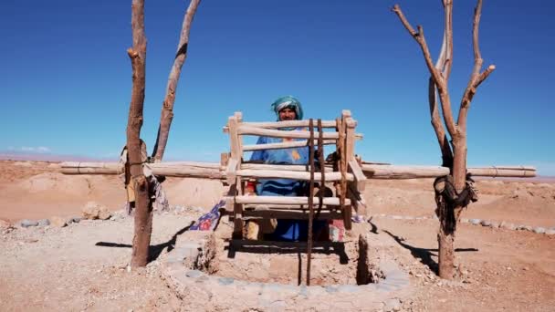 Man taking out water from well against desert landscape in Morocco — Stock Video
