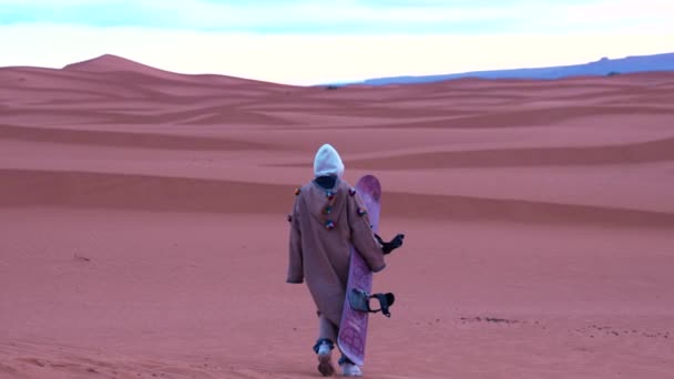 Kum tepelerinde gökyüzüne karşı yürüyen geleneksel giysili bir kız. — Stok video