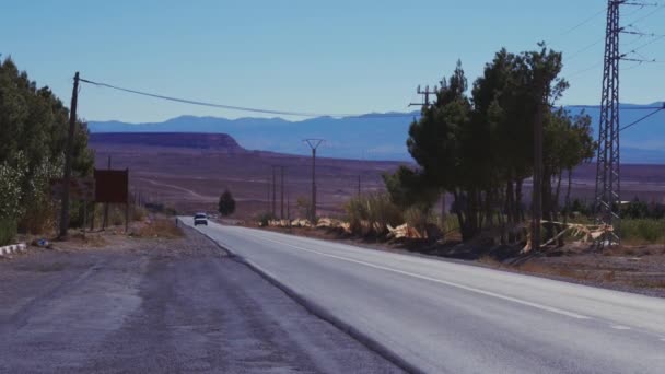 Szenische Ansicht eines Autos, das die leere Straße mit Gebirgskette hinunterfährt — Stockvideo