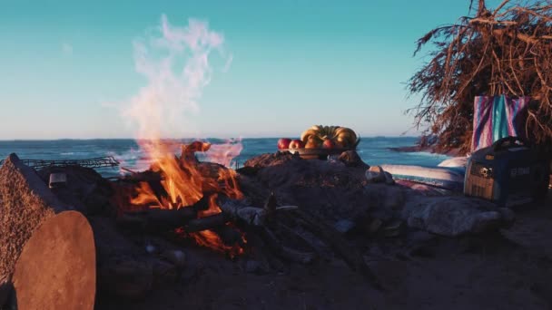 在美丽的落日下，在海滩用燃烧的柴火燃着篝火 — 图库视频影像