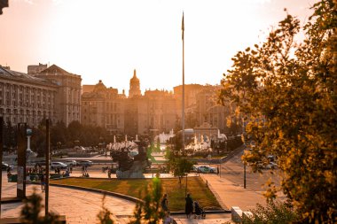 Kyiv, Ukrayna. 20 Temmuz 2021. Gün batımında şehir silueti, Independence Meydanı 'ndaki Globus merkez alışveriş merkezi Aziz Sophia Katedrali ve diğer kentsel binaların yanındaki çeşmeler.