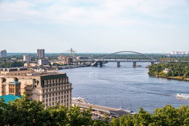 Kyiv, Ukrayna. 20 Temmuz 2021. Kemerli köprüsü, nehir yatağı ve nehir kıyısının solunda binaları olan güzel bir şehir.