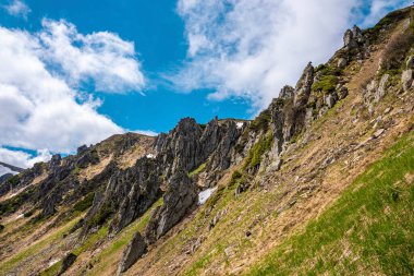 Dağ zirvesi ve dik yamaçlı kayalık uçurum ve bulutlu gökyüzüne karşı yosun. Gökyüzünün düşük açılı görüntüsü