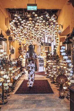 Dubai, BAE. 10 Şubat 2022. Al Jaber Galerisi 'nin hediyelik eşya dükkanından dekoratif geleneksel asma lambaları alan kadın.
