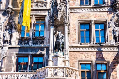 Almanya 'da Marienplatz belediye binası ile Münih silueti. Ukrayna 'daki savaşa destek için Münih, Almanya' da Ukrayna bayrakları.