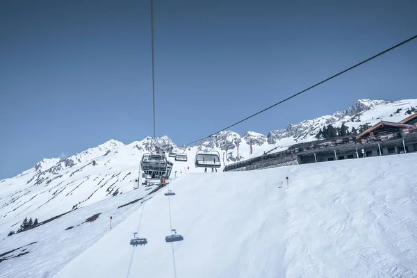 Elevador de esqui movendo-se sobre a gama de montanhas nevadas contra céu limpo — Fotografia de Stock