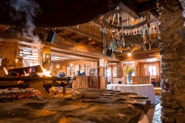 Sıcak bir otelde şömine yanıyor. Çiçek vazosu ve dekorasyon lobide. Köy restoranının içi..