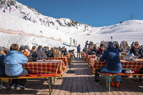 St. Anton am Arlberg. March 10, 2022. People sitting at outdoor cafe beside tables at ski resort chalet during skiing holiday, Tourists sitting at mountain cafe on sunny day