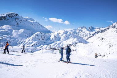 Aziz Anton am Arlberg. 10 Mart 2022. Kayakçılar güneşli bir günde, karlı dağlarda direkleri tutan kayakçılar, karlı dağlarda ayakta duran kayakçılar.