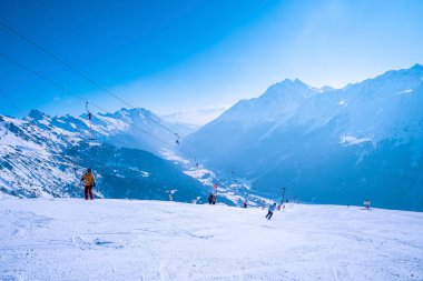 Aziz Anton am Arlberg. 10 Mart 2022. Kayak yapan insanlar güzel güneşli bir günde dağda karla kaplı dağlarda yürürken, dağ yamacında yürüyen kayakçılar giyerler.