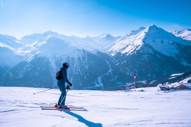 Kayakçı karla kaplı yamaçta kayak yapıyor. Mavi gökyüzüne karşı güzel bir dağ sırası. Turist kış boyunca macera sporu yapıyor.